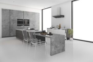 Nowoczesna kuchnia z meblami na wymiar w stylu industrialnym – szare fronty z efektem betonu, wyspa kuchenna z blatem imitującym beton, czarne dodatki i duże przeszklenia zapewniające naturalne światło. Przykład eleganckiej aranżacji mebli kuchennych na wymiar do nowoczesnego wnętrza.